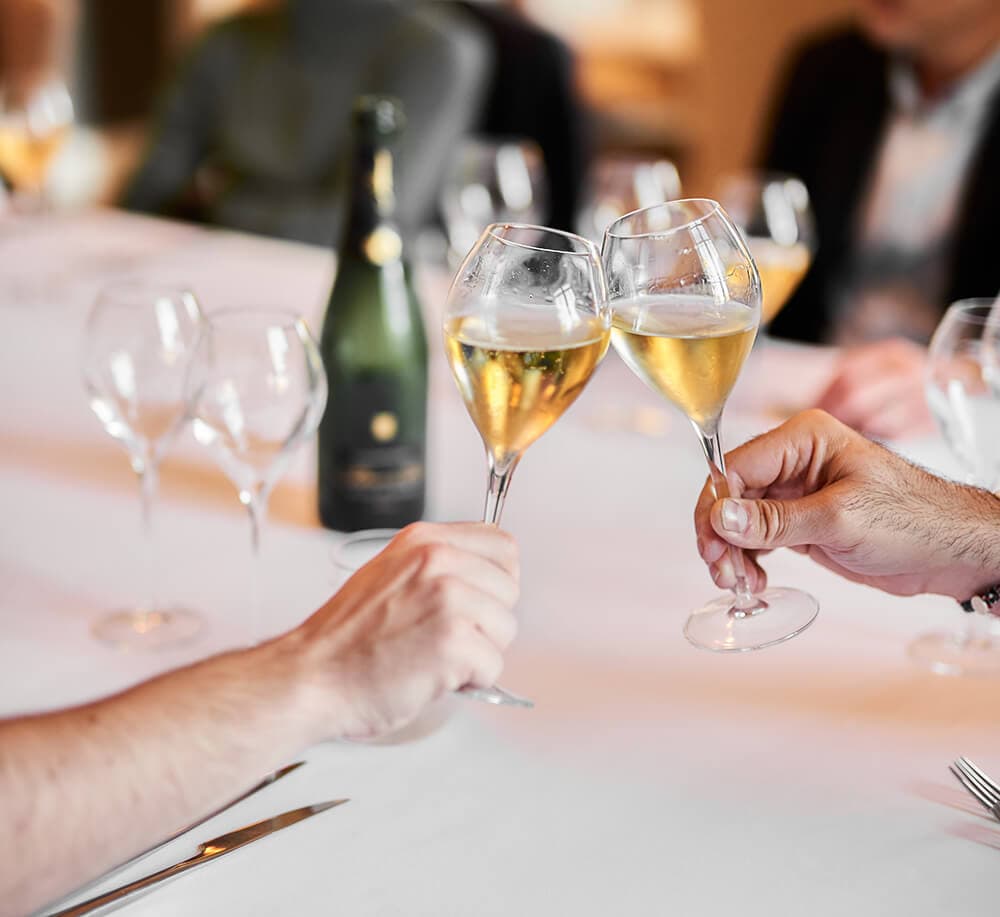Deux personnes trinquent avec leurs verres dans une ambiance chaleureuse et conviviale lors d’une dégustation.